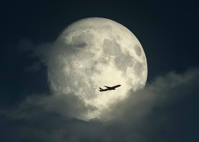 Airplane flying past the moon