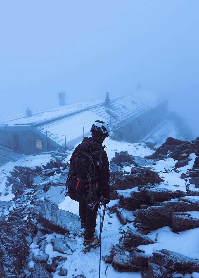 Mountaineer approaching mountain hut in snow