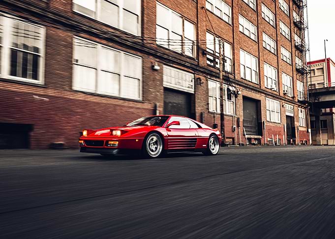 Red Ferrari driving down urban street