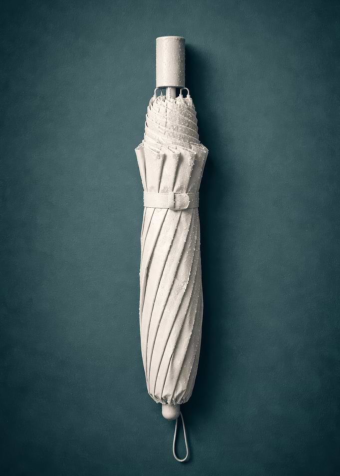 Closed White Umbrella on Teal Background