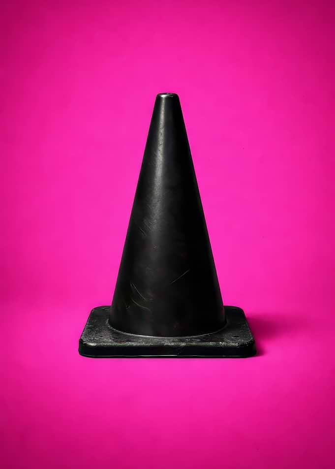Black traffic cone on pink background