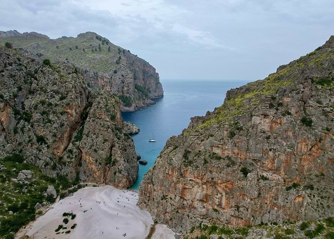 Dramatic Coastal Gorge with Beach and Sailboat