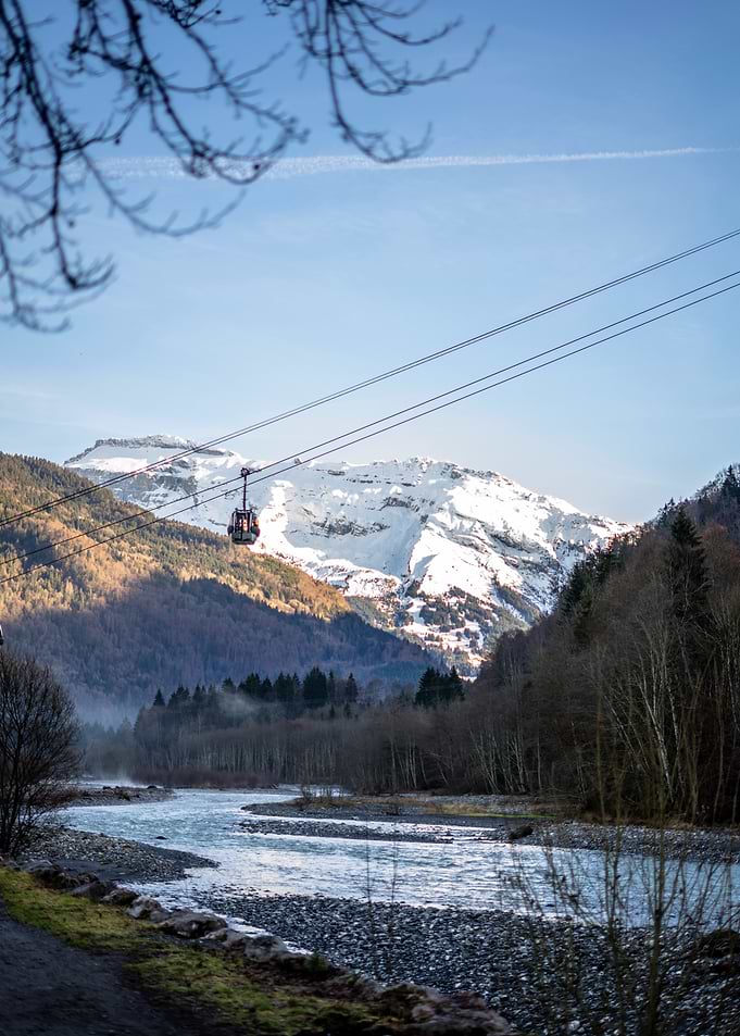 Cable Car Over Snowy Mountain River in the French Alps
