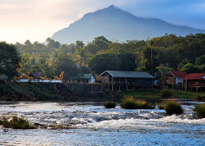 Laos River village at the foot of a misty mountain