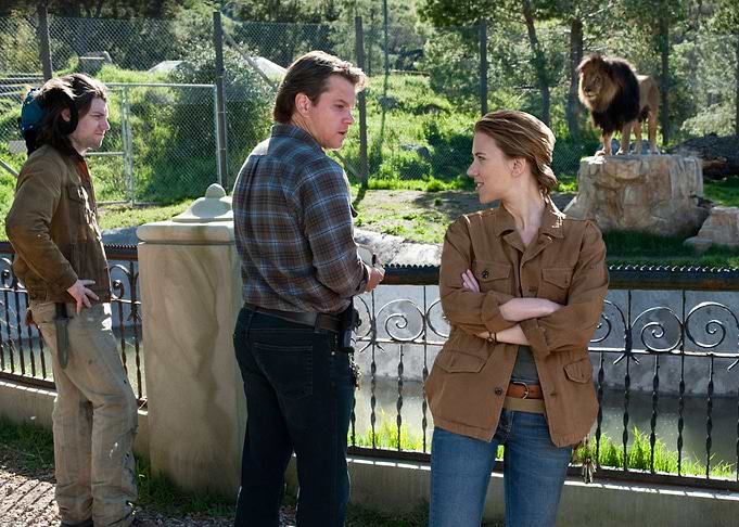 People observe a lion in an enclosure