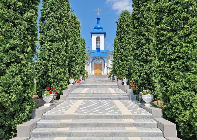 Church Entrance with Cypress Trees and Flowers