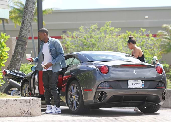 Man with drinks by a Ferrari