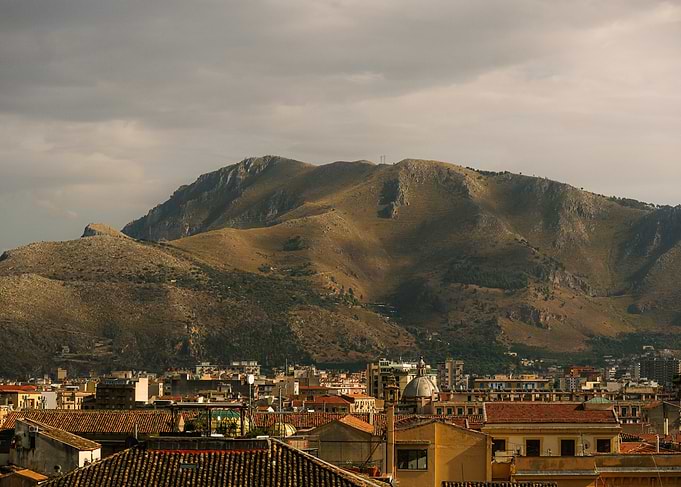 Cityscape with Mountains Under Cloudy Sky