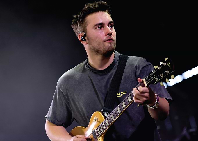 Musician playing guitar on stage Sam Fender