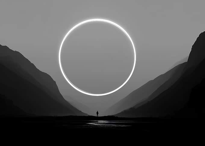 Man in front of a glowing ring in mountains