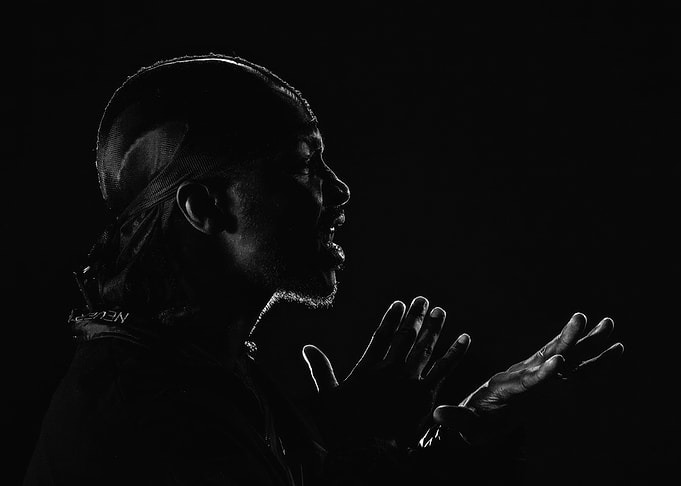 jme in silhouette speaking with hands raised