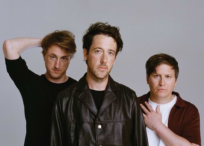 Three men posing for a photo the wombats