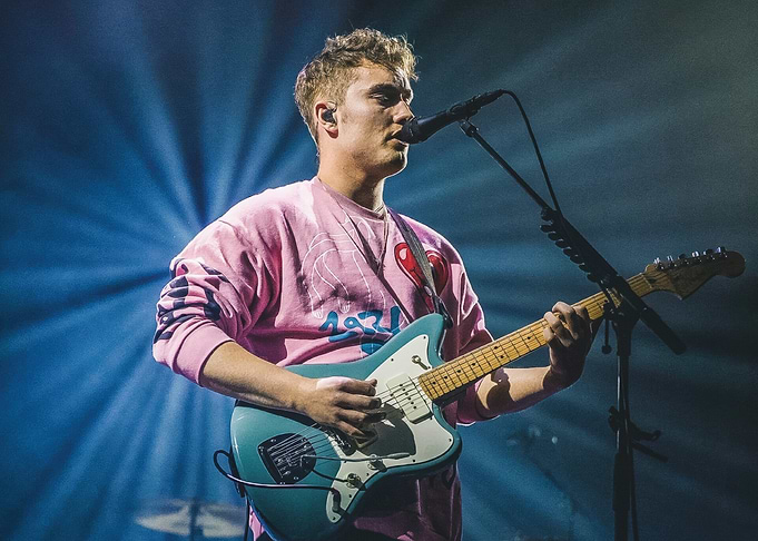 Musician playing guitar on stage Sam Fender