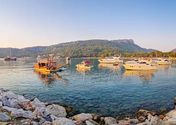 Boats in a clear blue bay at sunset