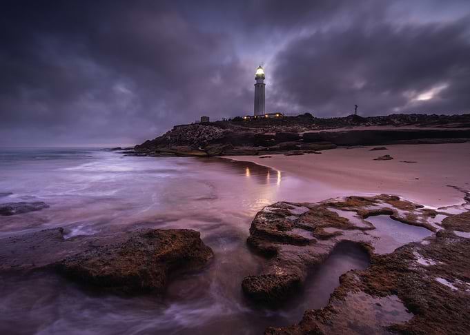 Lighthouse on a rocky coast at dusk