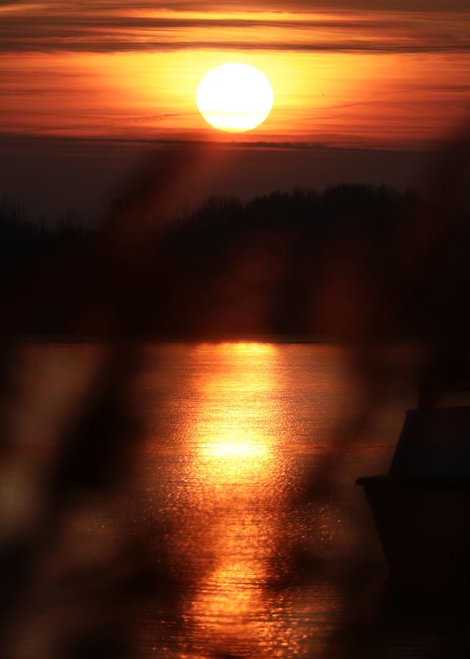 Sunset over a calm lake with a boat