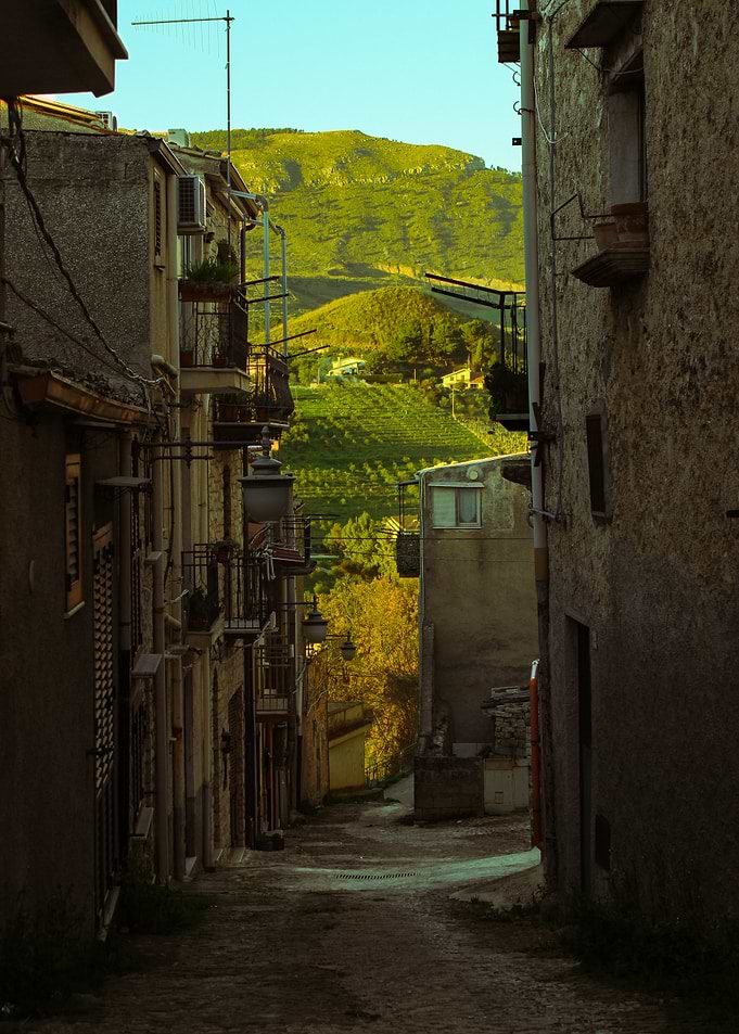 Narrow Italian Street with Green Hills Background