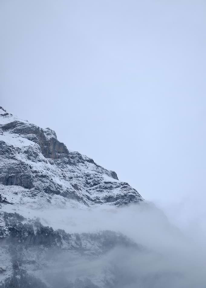 Misty Snow-Covered Mountain Cliff in Winter