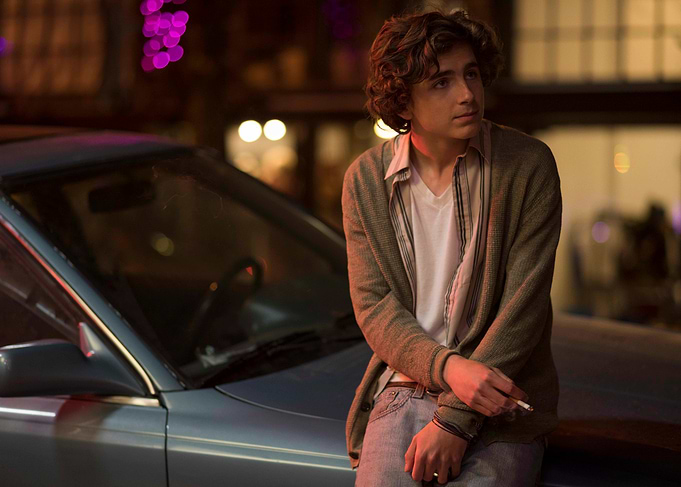 Young man leaning on a car at night