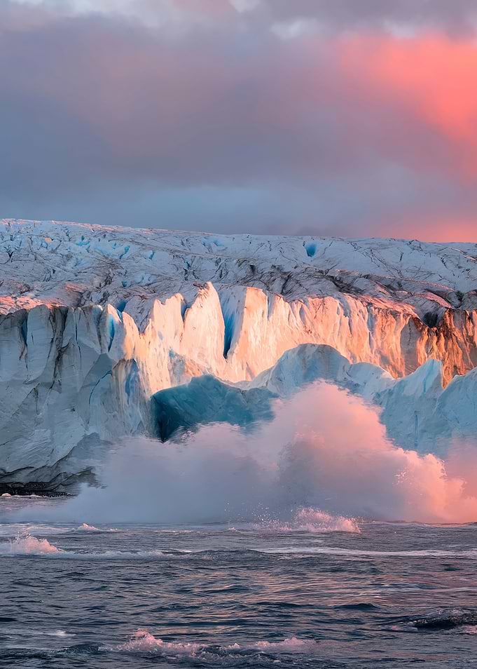Glacier calving into the ocean at sunset
