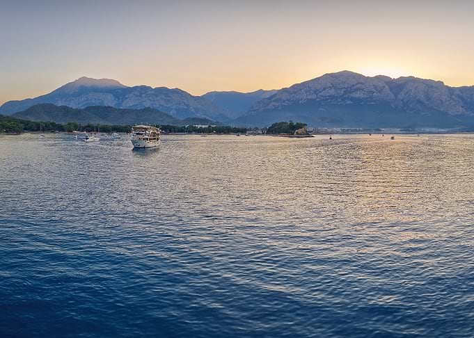 Sunset over a coastal mountain range with boats
