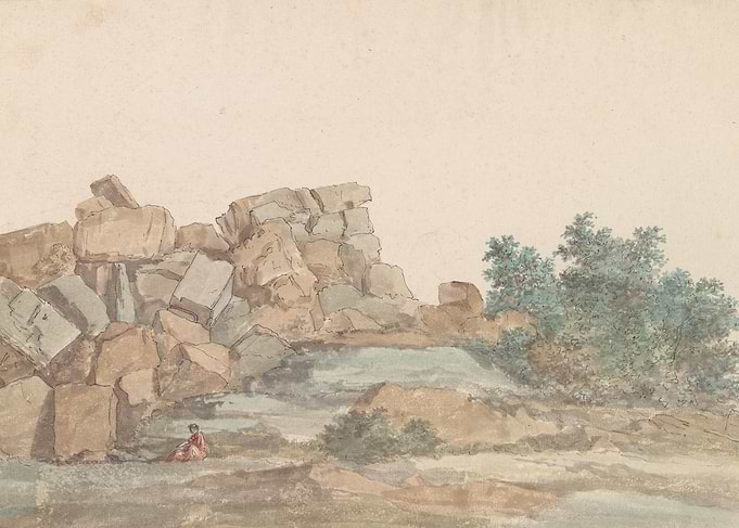 Person sitting by large rocks and trees