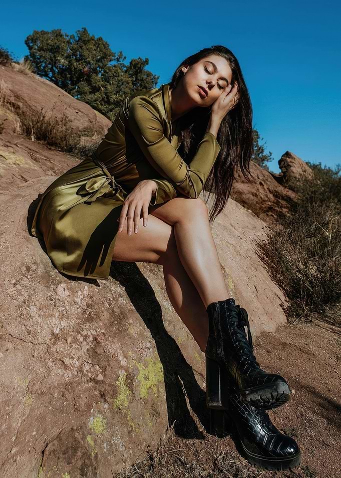 kira kosarin in green dress sitting on rock