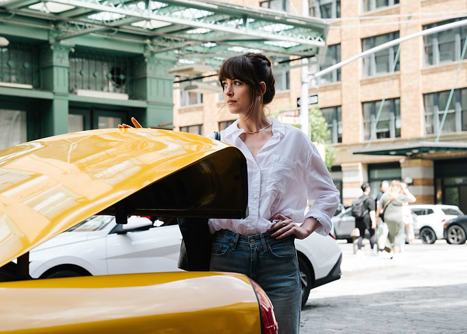 Woman by yellow car in city