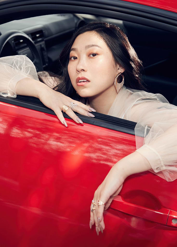 awkwafina leaning out of red car
