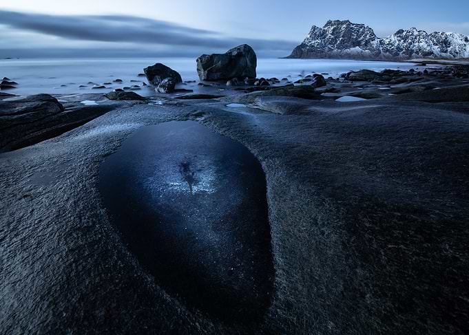 Twilight seascape with rocky shore and mountains