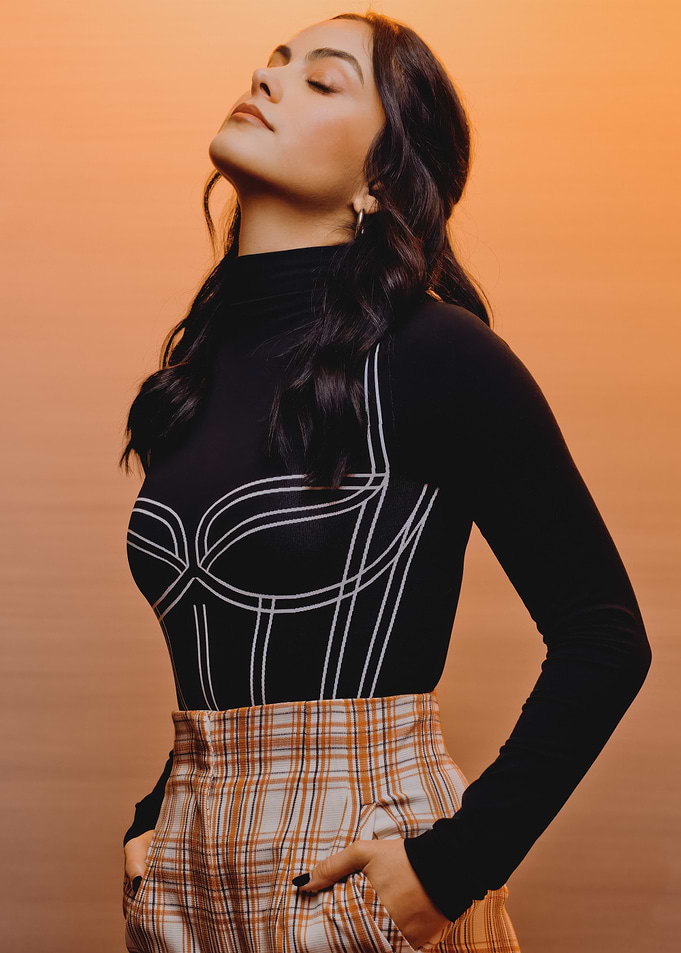 Camila Mendes in black top and plaid skirt