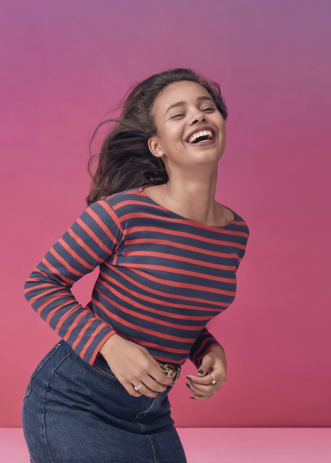 Alisha Boe laughing in striped shirt and denim skirt