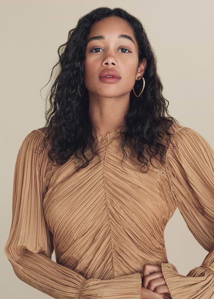 Laura Harrier in a pleated tan dress