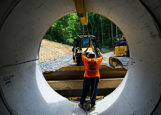 Construction worker guiding pipe placement