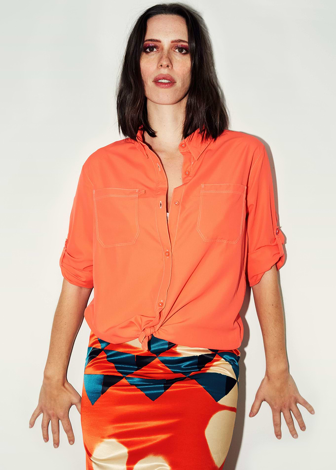 Rebecca Hall in orange shirt and patterned skirt