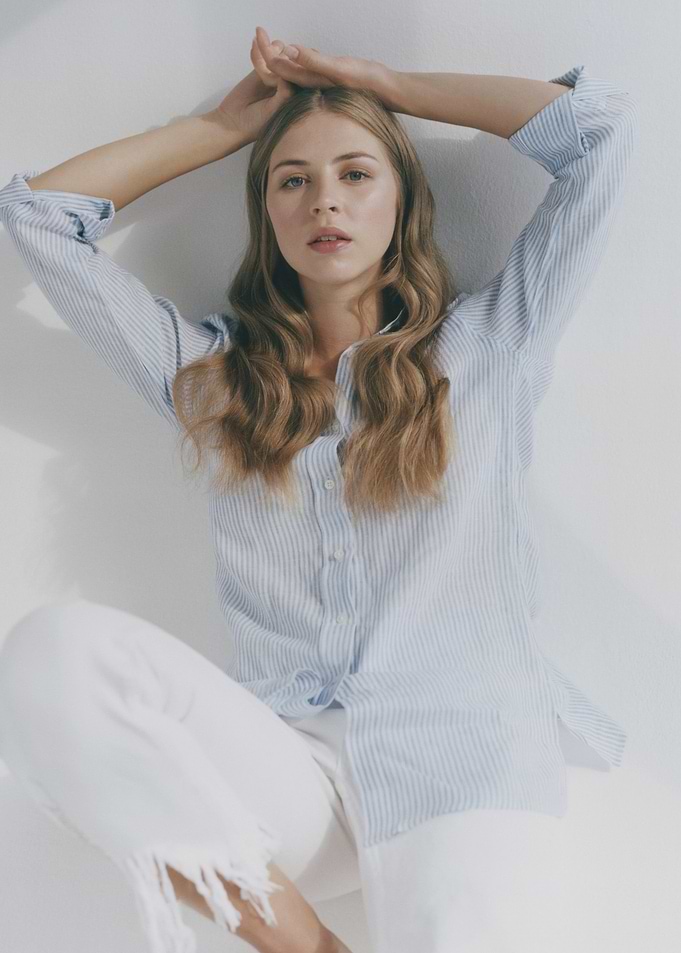 Hermione Corfield in striped shirt and white pants