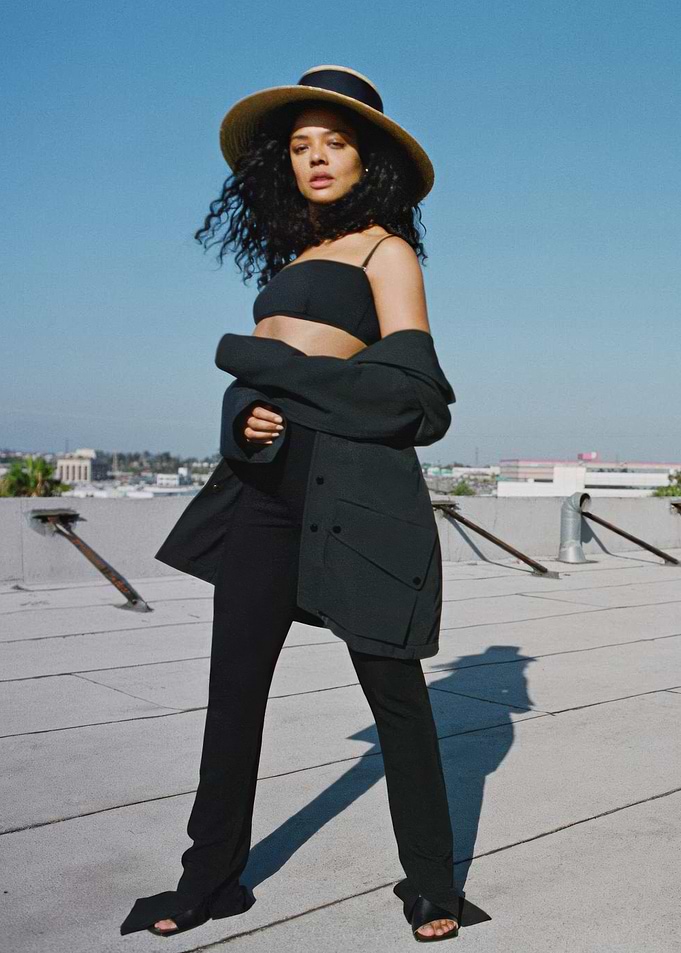 Tessa Thompson in hat and black outfit on rooftop