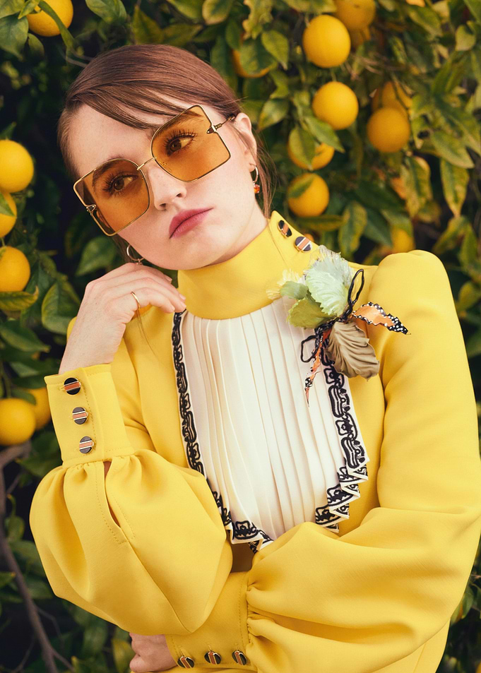 Kaitlyn Dever in yellow dress with orange sunglasses