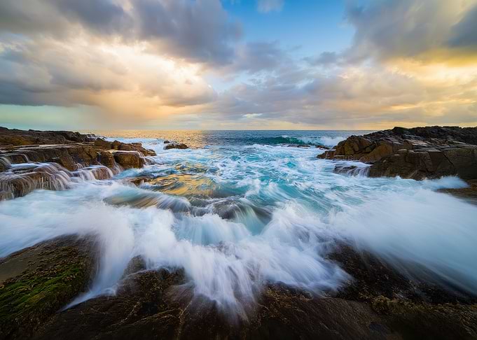 Waves crashing on rocky shore at sunset
