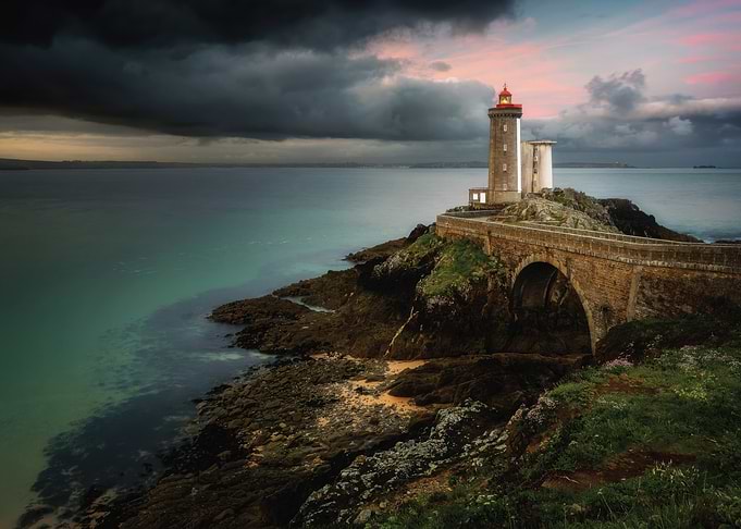 Lighthouse on a rocky island at sunset