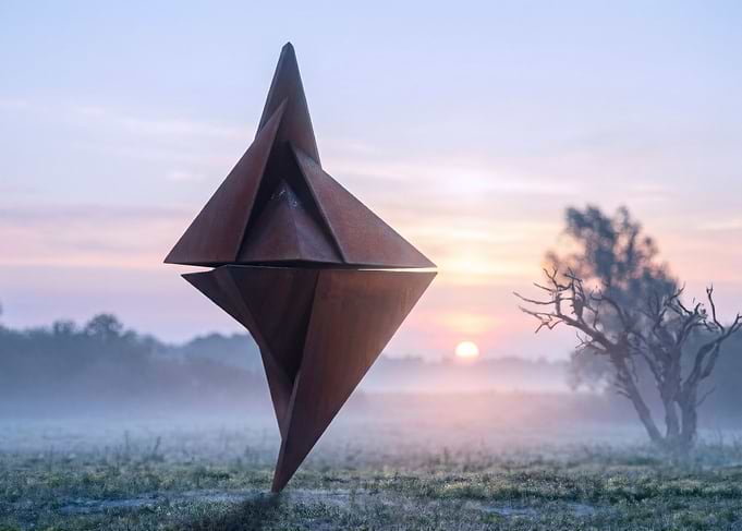 Sculpture in misty sunrise landscape