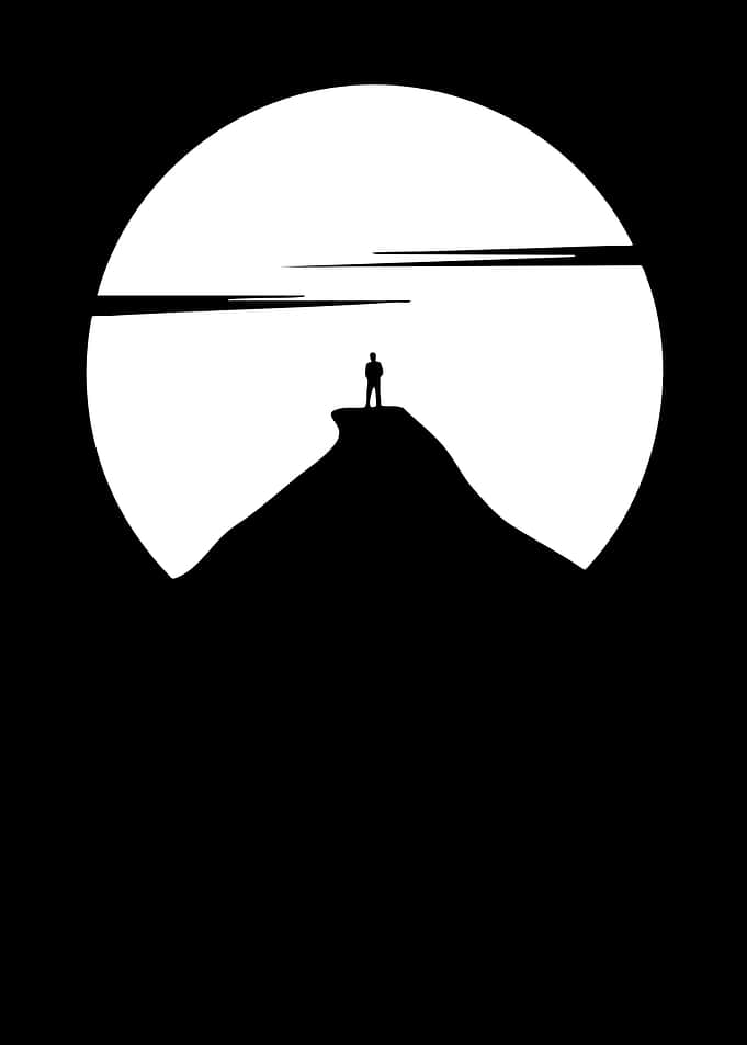 Lone figure on mountain peak at sunset