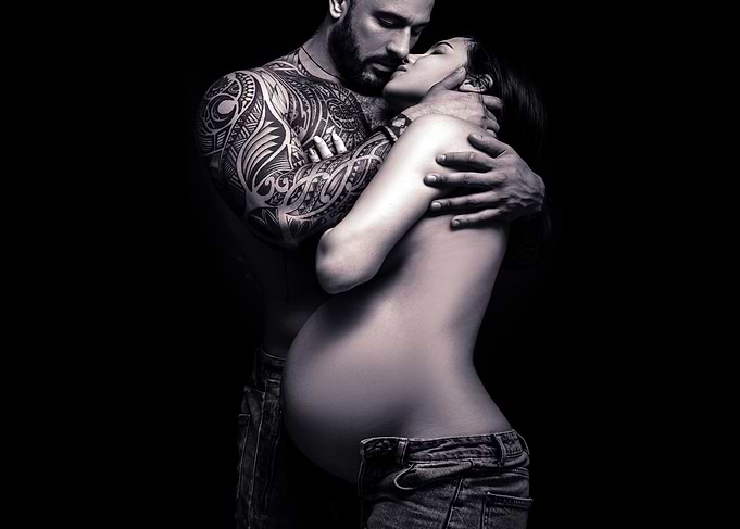Tattooed Man Embraces Pregnant Woman