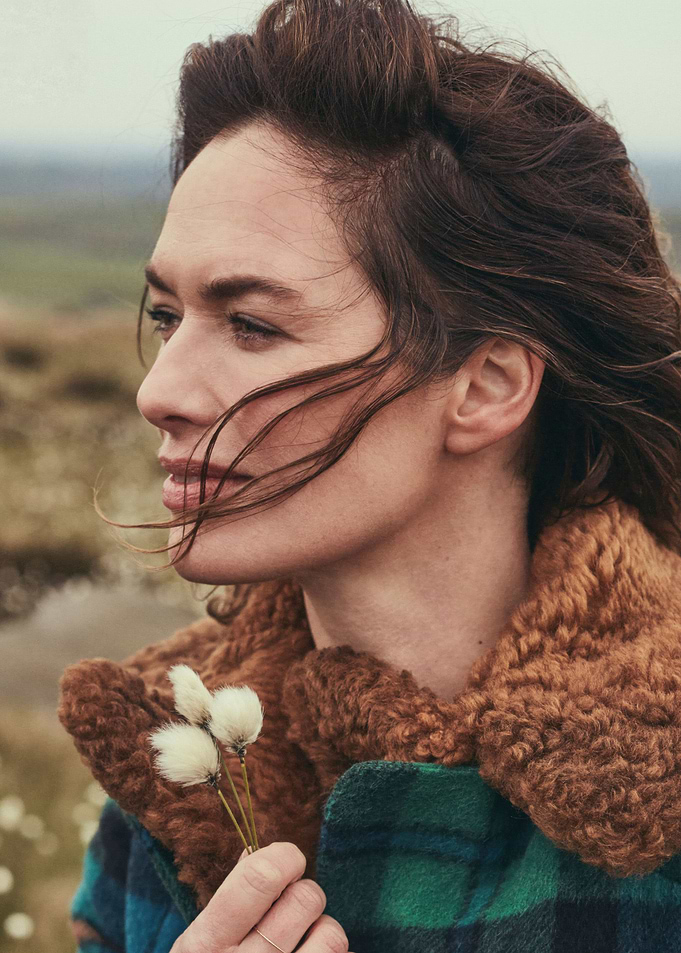 Lena Headey in plaid coat holding cotton flowers