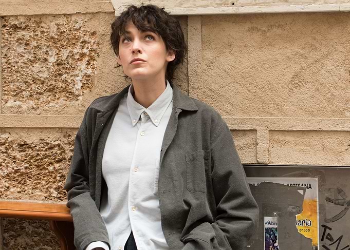 Woman in casual outfit leaning against wall