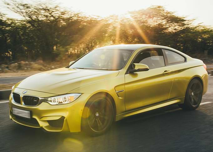 Yellow BMW M4 Coupe Driving at Sunset