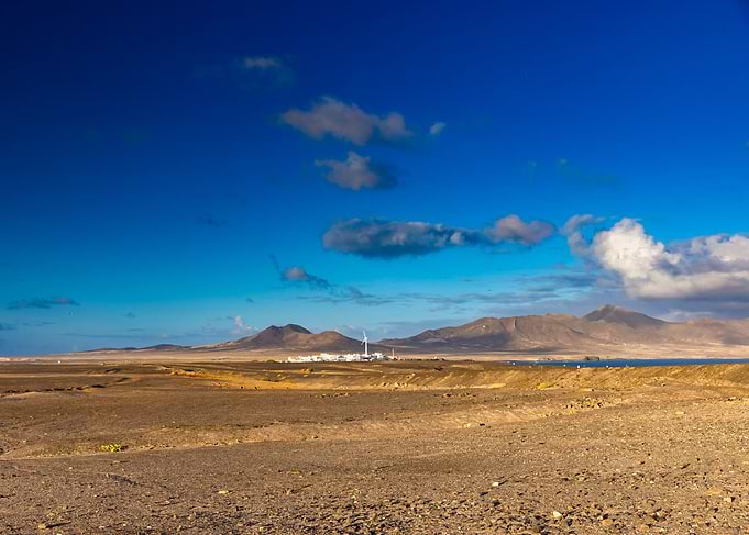 Arid Landscape with Distant Mountains and Wind Turbine