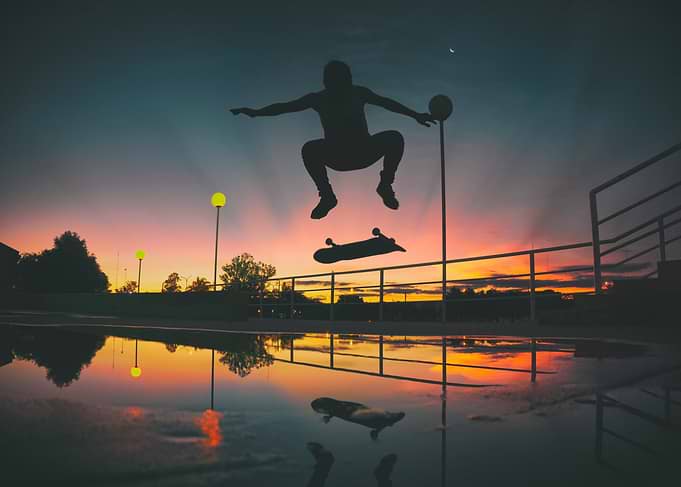 Skateboarder silhouetted against sunset