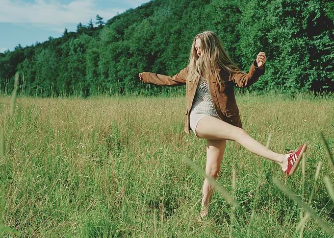 Woman in field with brown jacket