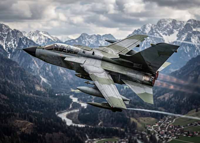 Military Jet Flying Over Mountains